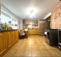 A kitchen in a family house with wooden cabinets, tiles, and a dining table.