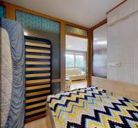 A room with a bed next to a glass partition overlooking a sofa in commercial premises.