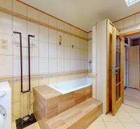 Bathroom with a bathtub, washing machine, and wooden door in commercial premises.