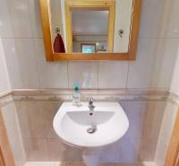 Sink with mirror, tiles, and soap dispenser in commercial premises.