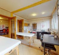 Massage room with loungers and a work table, commercial space with bright decor.