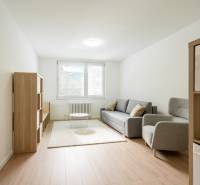 Living room with a light sofa and wooden shelves in a 3-room apartment.