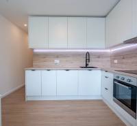 A modern kitchen in a 3-room apartment with white cabinets and a black faucet.