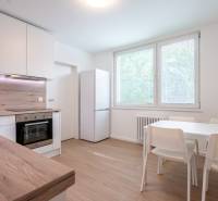 A kitchen in a 3-room apartment with white furniture and a table, wooden details.