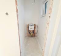 Preparation for installing a toilet in the bathroom of a family house with a window and white walls.
