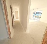 A hallway in a family house with unfinished door openings and a view of the terrace.