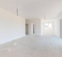 A spacious room in a family house with large windows and an unfinished floor.