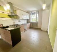 A kitchen in a 3-room apartment with a stove, a hood, and an open window.
