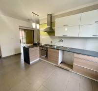 A kitchen in a 3-room apartment with a cooktop, white and wooden cabinets.