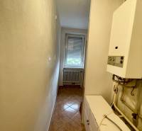 A narrow corridor with a boiler and a window in a 3-room apartment.