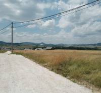 The landscape in Kunerad with a paved road, residential plots, and a view of the mountains.