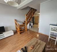 Interior of a 3-room apartment with a staircase and wooden floors, TV stand and table.