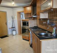 A kitchen in a 3-room apartment with a kitchen unit, appliances, and tiles.