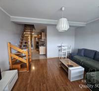 Living room in a 3-room apartment with a sofa, wooden stairs, and a television.