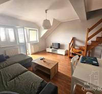 Living room with a sofa, table, and stairs in a three-room apartment.