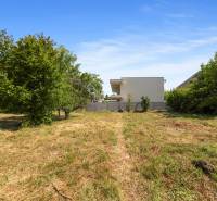 A plot in Dobrohošť for living with trees and neighboring houses in the background.