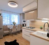 A kitchen unit with wooden paneling, a dining table, and lighting in a 2-room apartment.