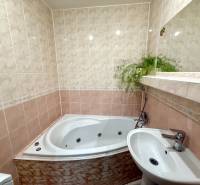 A bathroom with light tiles, a bathtub, and a sink in a 4-room apartment.