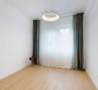 A room with a wooden floor, white wall, green curtains, and stylish lighting.