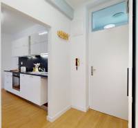 A kitchen in a 2-room apartment with white cabinets and wooden flooring.