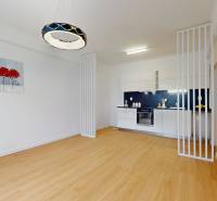 A kitchen in a 2-room apartment with wooden flooring and white furniture.
