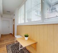 A hallway in a 2-room apartment with wooden paneling and a table with a plant.