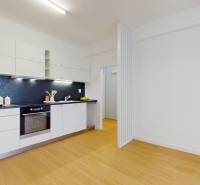 A kitchen in a 2-room apartment with white cabinets and wooden flooring.