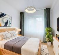 Bedroom with a bed, nightstands, a painting, and a television in a two-room apartment.