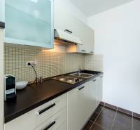 A kitchen in a studio apartment, with white cabinets and a dark countertop.