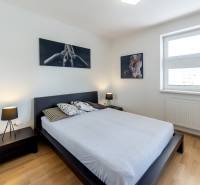 Bedroom with a bed, nightstands, and art photographs in a studio apartment.