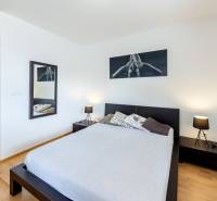 A bedroom in a studio apartment with a bed, nightstands, and decorations.