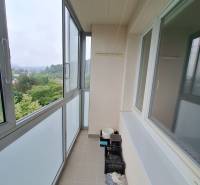 Enclosed balcony in a 3-room apartment with a view of greenery and surrounding hills.