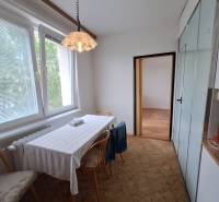 Dining table with chairs in a 3-room apartment, minimalist furnishings, white walls.