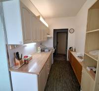 A narrow kitchen with a wooden countertop in a 3-room apartment, white cabinets, patterned floor.