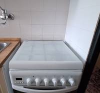 A kitchen in a 3-room apartment with an electric stove and a range hood.