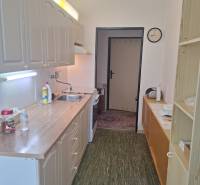 A kitchen in a 3-room apartment, with a wooden cabinet, a sink, and a clock on the wall.