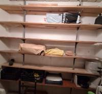 Shelf storage space in a 3-room apartment with wooden shelves and various items.