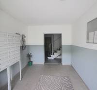 The entrance hall of an apartment building with a staircase, mailboxes, and a bulletin board.