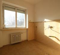 An empty kitchen with a window in a 3-room apartment, unfurnished, light tiles.