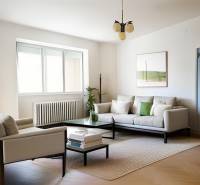 A bright living room with a sofa, an armchair, and plants in a three-room apartment.