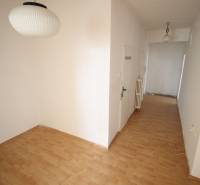 A hallway in a 3-room apartment with light, wooden flooring, and white walls.