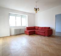 Living room in a 3-room apartment with a red sofa and wooden floor.