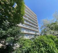 The image shows an apartment building on Na Hrebienku street, surrounded by greenery.
