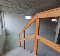 Unfinished interior of a gastro space with a staircase and a concrete ceiling.