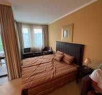 A bedroom with a bed and a TV in a holiday apartment, bright curtains.