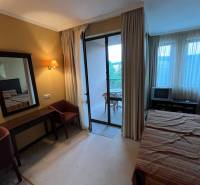 Bedroom of a holiday apartment with a view through the balcony doors, light furniture.