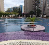 A swimming pool at the apartments on the Sunny Beach surrounded by sunbeds and greenery.