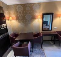 Dining room in a holiday apartment with a wallpapered wall, a coffee table, and two chairs.