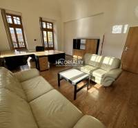 An office interior with leather sofas, wooden flooring, and large windows.
