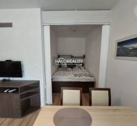 Interior of a 1-room apartment with a television, double bed, and dining table.